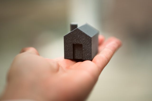 Mano sujetando una figura de una casa